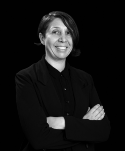 Black and white portrait of Professor Marcela Oteíza Silva smiling with her arms crossed.